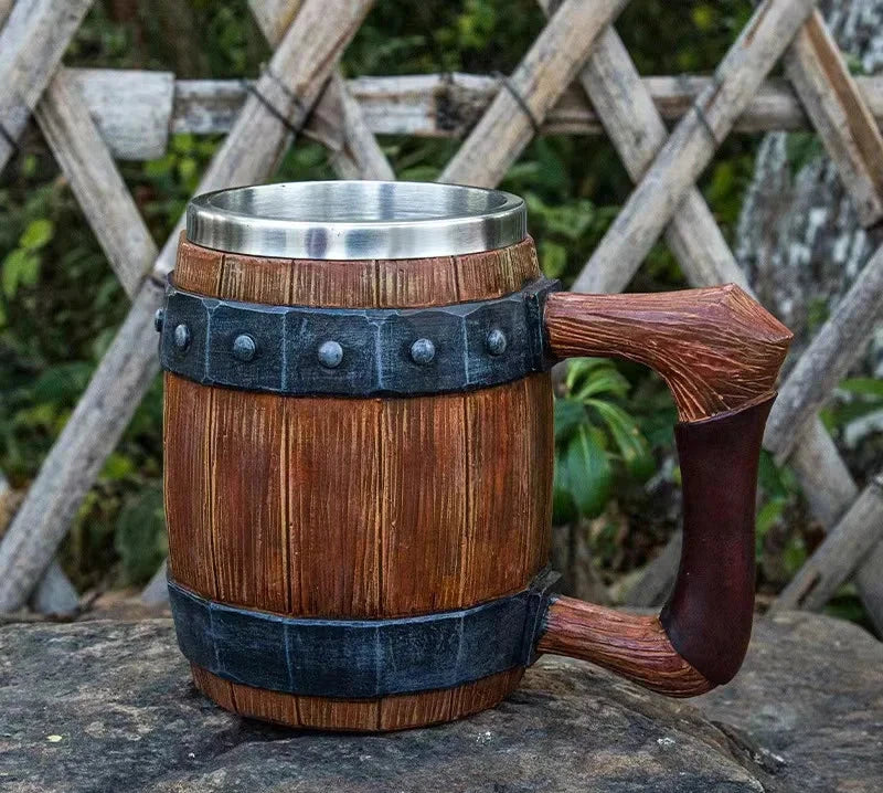 Wooden mug with metal rim and handle on a stone surface with a wooden fence background