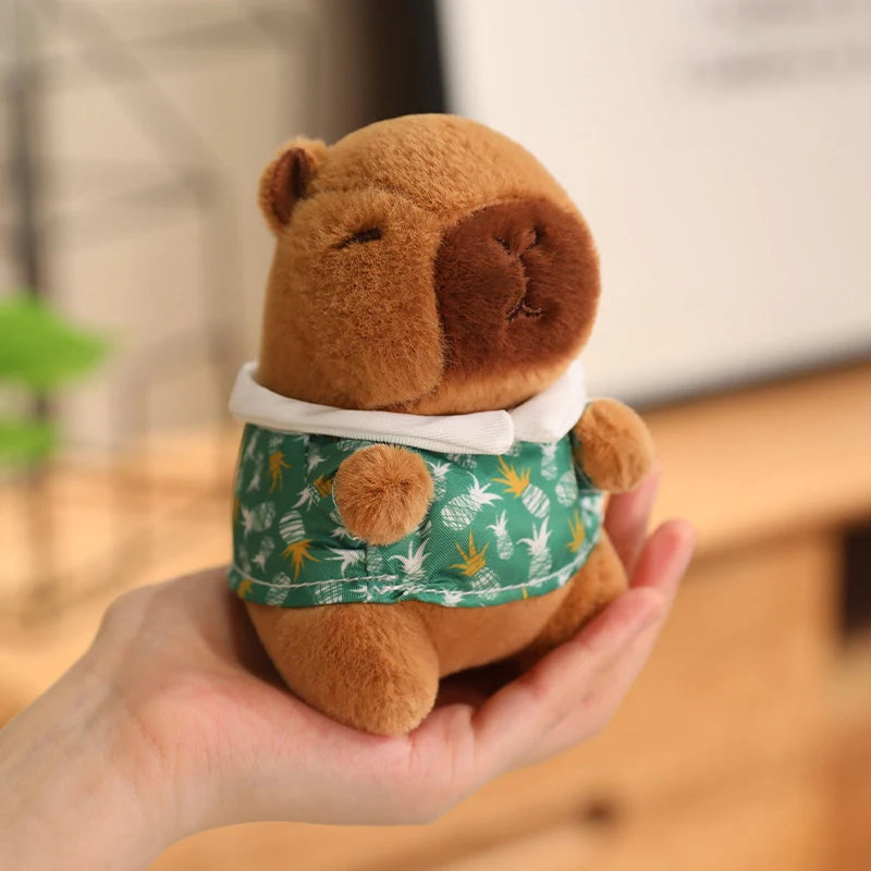 Plush toy bear wearing a green shirt with animal patterns held in a hand.